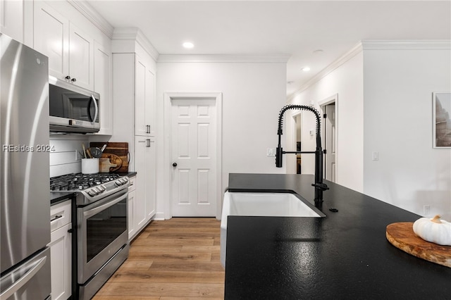 kitchen with sink, white cabinets, light hardwood / wood-style floors, stainless steel appliances, and crown molding