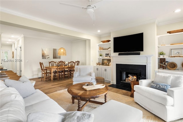 living room featuring crown molding, light hardwood / wood-style flooring, and built in features