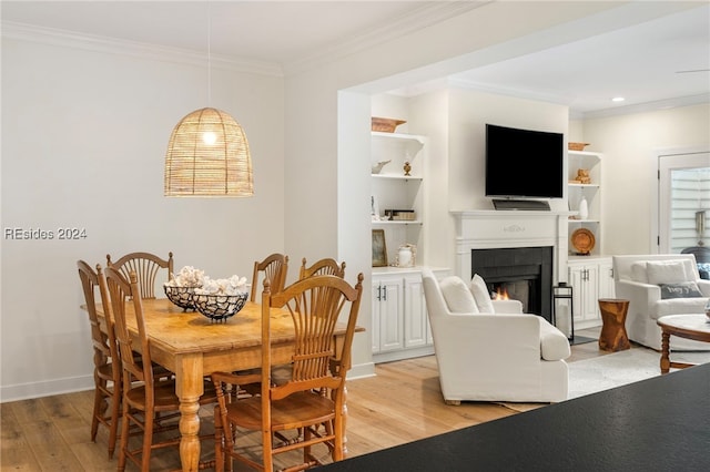 dining room featuring built in shelves, crown molding, and light hardwood / wood-style flooring