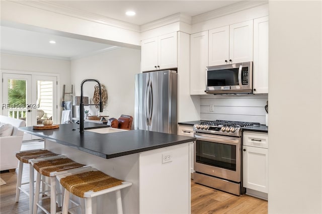 kitchen with stainless steel appliances, a center island with sink, and white cabinets