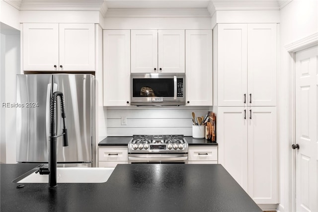 kitchen with crown molding, appliances with stainless steel finishes, white cabinets, and backsplash