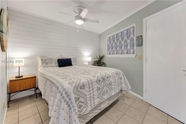 bedroom with crown molding, light tile patterned floors, ceiling fan, and wood walls