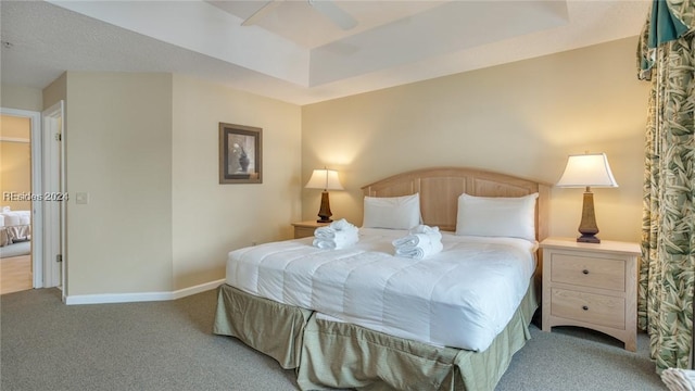 carpeted bedroom with ceiling fan and a tray ceiling