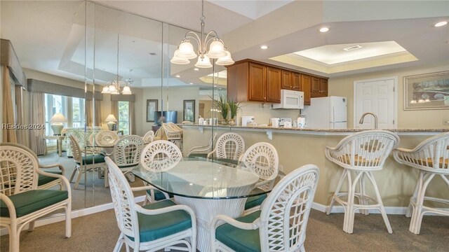 dining space featuring carpet floors, a notable chandelier, and a tray ceiling