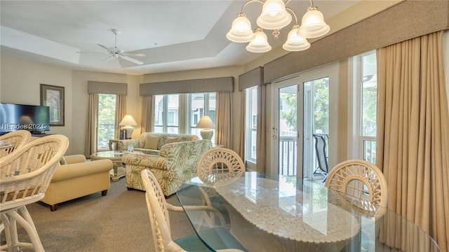 interior space featuring a tray ceiling and ceiling fan with notable chandelier