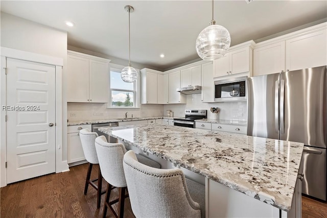 kitchen with stainless steel appliances, a kitchen island, hanging light fixtures, and white cabinets