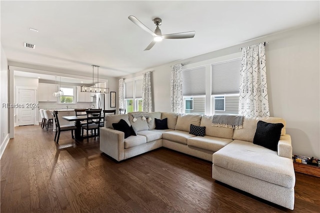 living room featuring dark hardwood / wood-style flooring and ceiling fan with notable chandelier