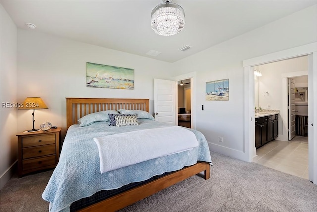 bedroom featuring sink, ensuite bath, light colored carpet, and a chandelier