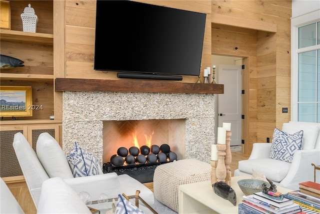 living room featuring a tiled fireplace and wood walls