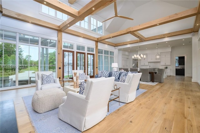 living room with a high ceiling, ceiling fan with notable chandelier, and light hardwood / wood-style floors