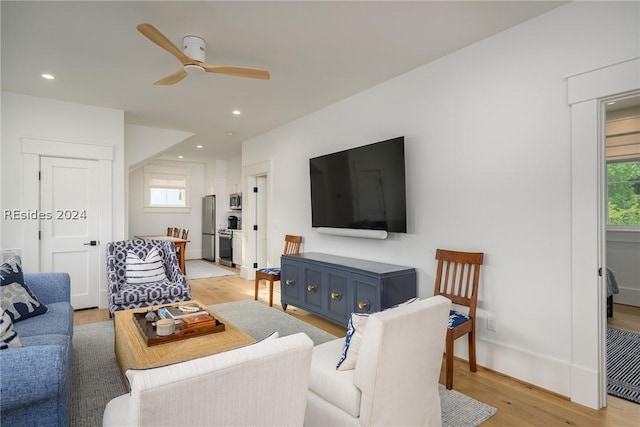 living room with light hardwood / wood-style flooring and ceiling fan