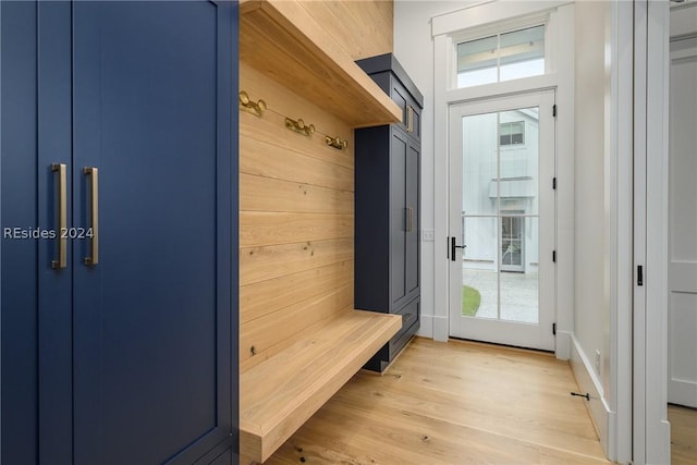 mudroom with light hardwood / wood-style flooring and wood walls