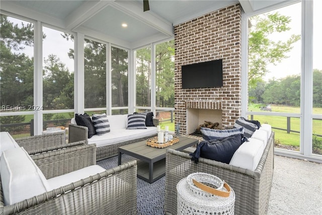 sunroom featuring an outdoor brick fireplace, a healthy amount of sunlight, and beamed ceiling