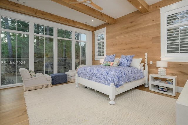 bedroom with beamed ceiling, wooden walls, hardwood / wood-style floors, and ceiling fan