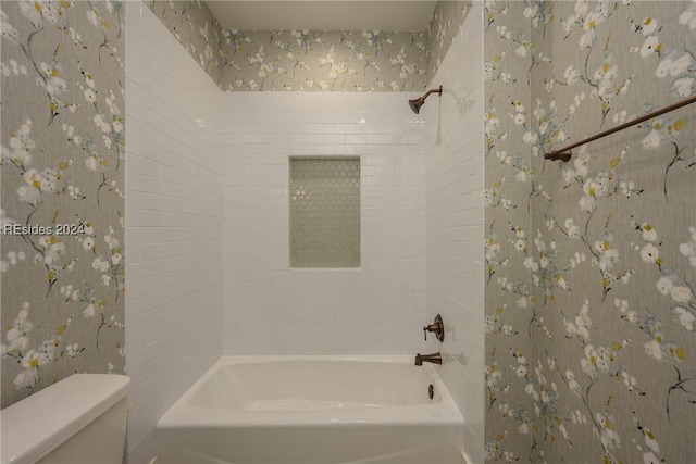 bathroom with toilet and tiled shower / bath