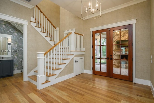 entryway with ornamental molding, light hardwood / wood-style flooring, a chandelier, and french doors