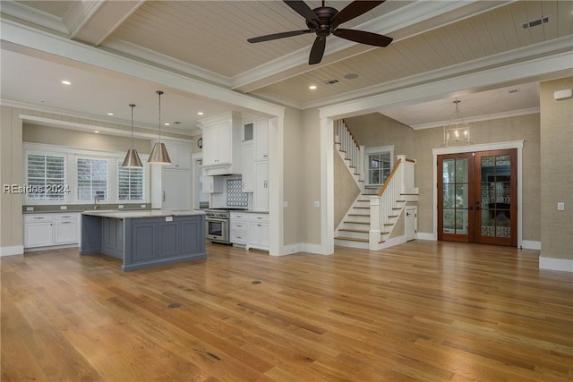 kitchen with white cabinetry, decorative light fixtures, decorative backsplash, a kitchen island, and high end stove