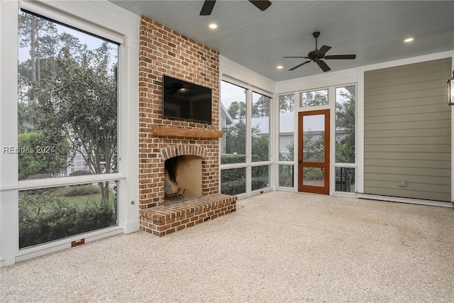 unfurnished sunroom featuring a brick fireplace and ceiling fan