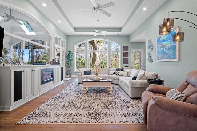 living room featuring ceiling fan, a tray ceiling, and hardwood / wood-style floors