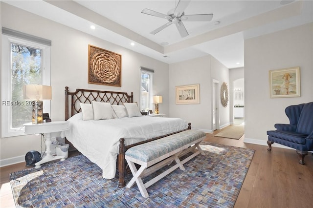 bedroom with ceiling fan, ensuite bathroom, multiple windows, and light wood-type flooring