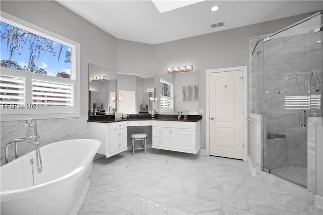 bathroom with vanity, shower with separate bathtub, a healthy amount of sunlight, and tile walls