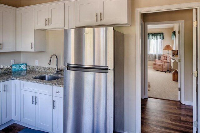 kitchen featuring sink, stainless steel fridge, light stone countertops, and white cabinets