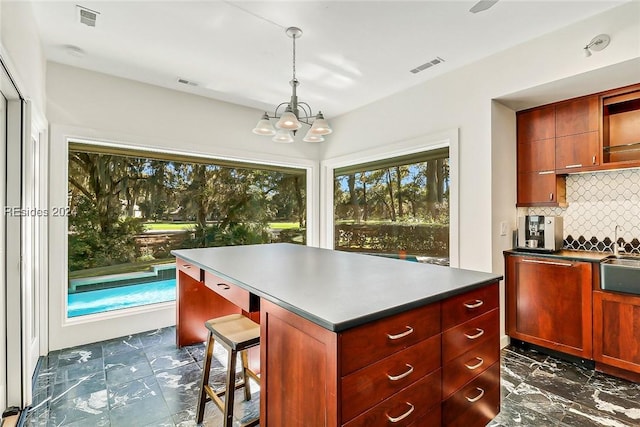 kitchen featuring a kitchen island, decorative light fixtures, sink, dishwashing machine, and backsplash