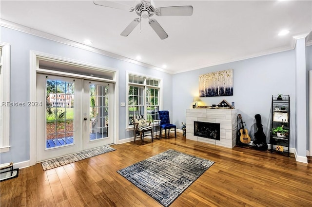 living room with crown molding, a tile fireplace, ceiling fan, hardwood / wood-style floors, and french doors