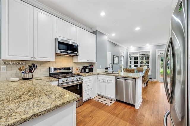 kitchen featuring sink, stainless steel appliances, light stone countertops, white cabinets, and kitchen peninsula