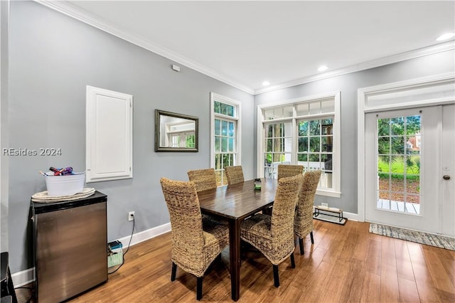 dining room with ornamental molding and light hardwood / wood-style flooring