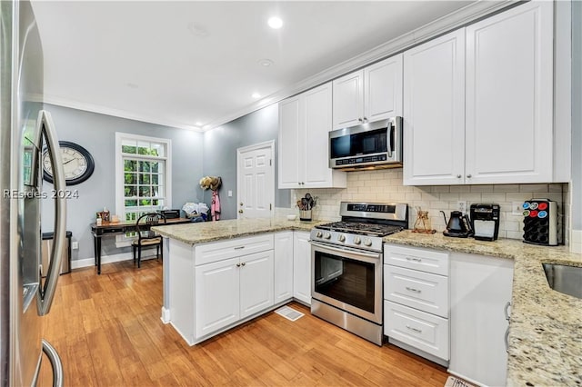 kitchen with white cabinetry, light stone counters, stainless steel appliances, and kitchen peninsula