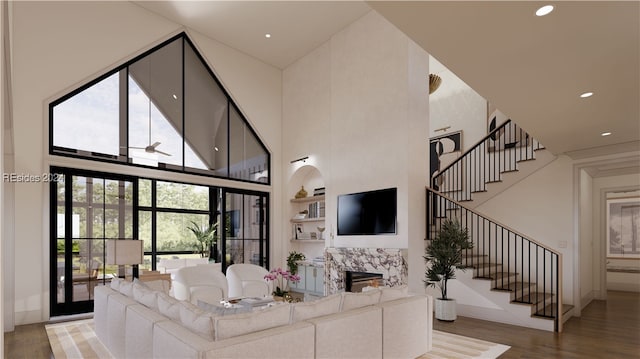 living room featuring a high ceiling, wood-type flooring, and built in shelves