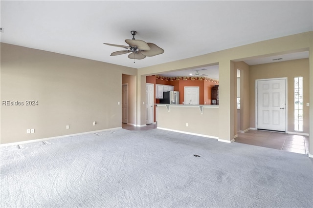 unfurnished living room with light carpet and ceiling fan