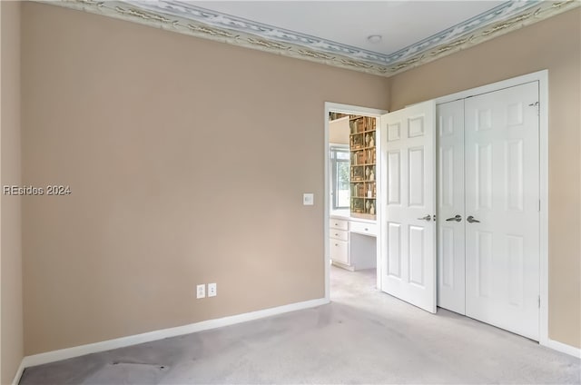 unfurnished bedroom with light colored carpet and a closet