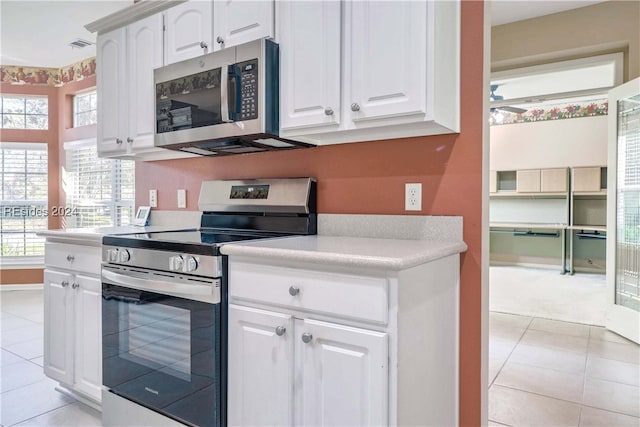 kitchen featuring white cabinetry, stainless steel appliances, light tile patterned floors, and plenty of natural light