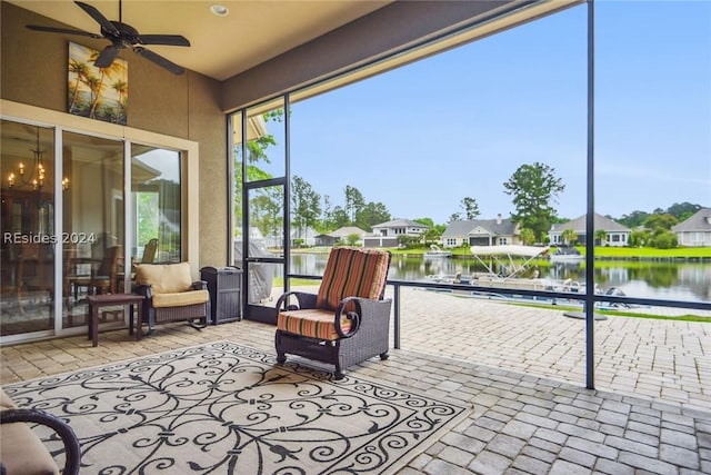 sunroom / solarium with a water view and ceiling fan with notable chandelier