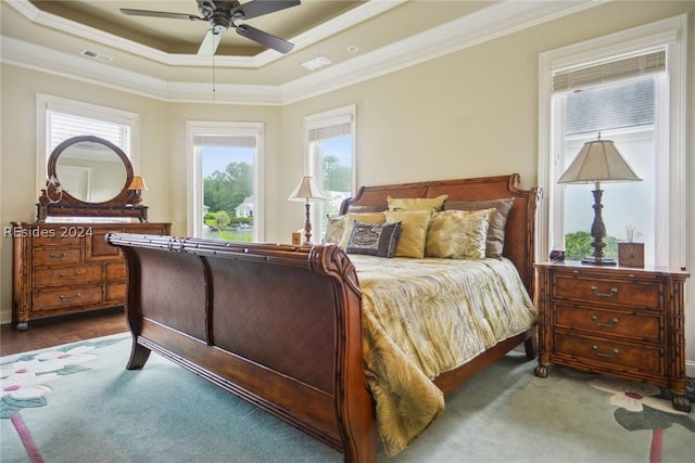 bedroom with crown molding, hardwood / wood-style floors, ceiling fan, and a tray ceiling