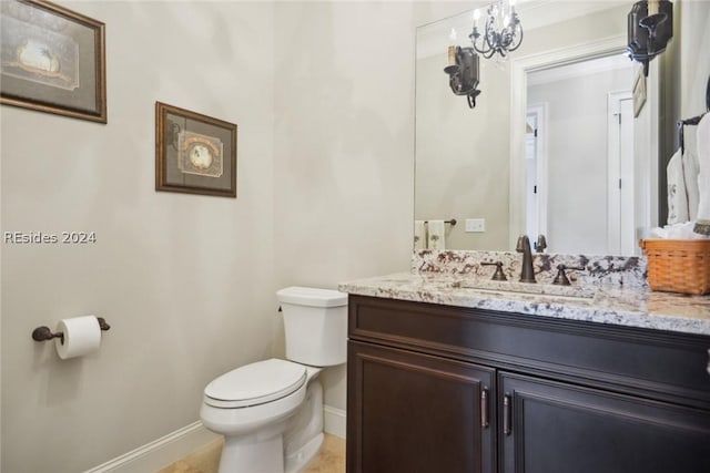 bathroom with an inviting chandelier, vanity, and toilet