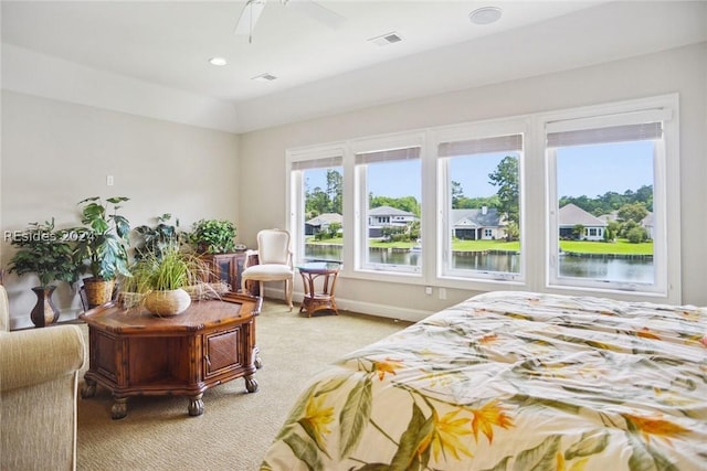 bedroom with a water view, light carpet, and ceiling fan