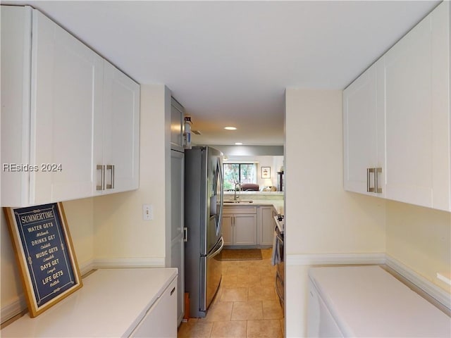 kitchen featuring sink, light tile patterned floors, white cabinets, and stainless steel refrigerator with ice dispenser