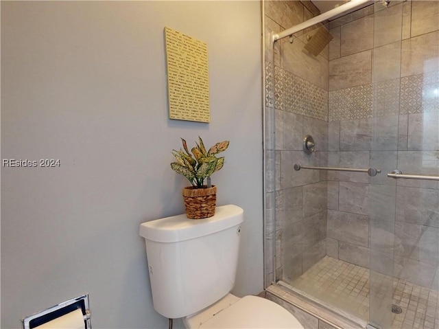 bathroom featuring toilet and a shower with shower door