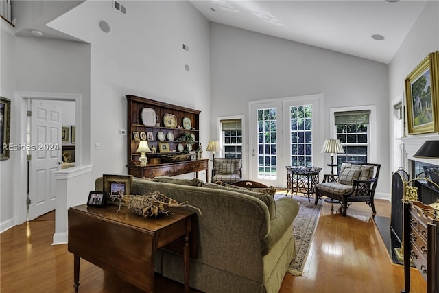 living room featuring high vaulted ceiling, a fireplace, and light hardwood / wood-style floors