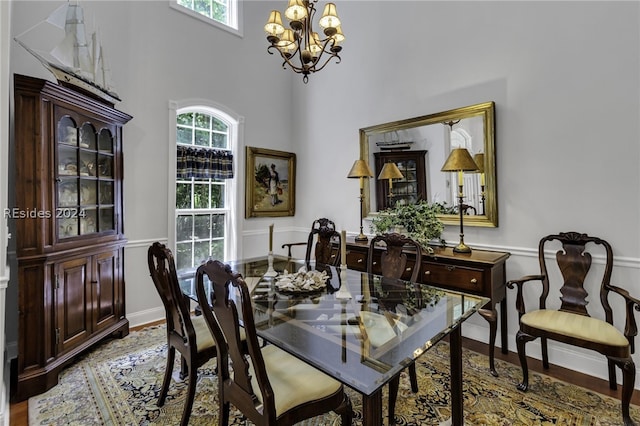 dining space featuring an inviting chandelier, a towering ceiling, and light hardwood / wood-style flooring