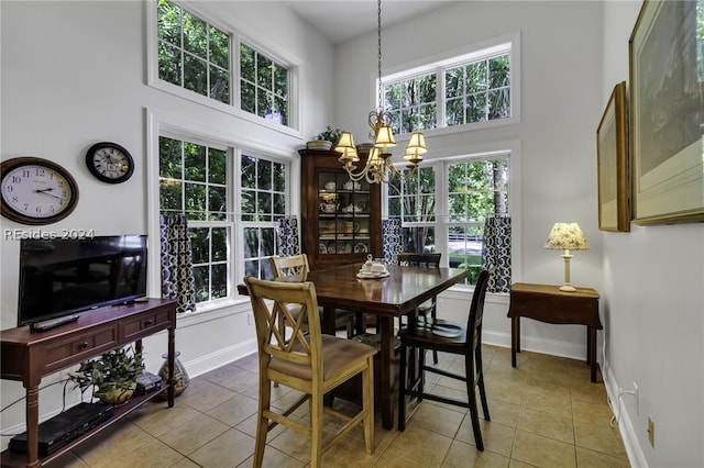 dining space featuring an inviting chandelier, a healthy amount of sunlight, tile patterned flooring, and a high ceiling