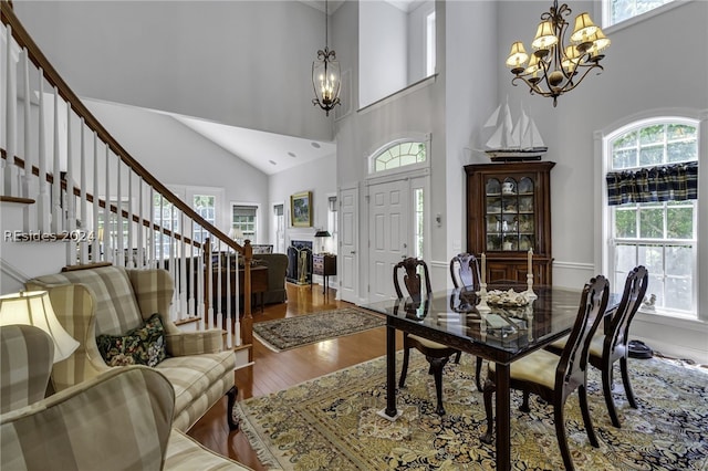 dining room with a towering ceiling, wood-type flooring, and a chandelier