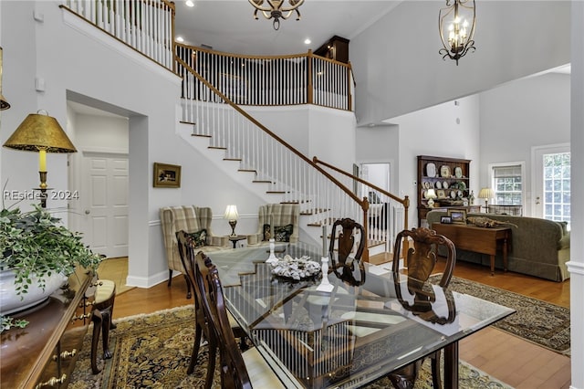 dining room with a towering ceiling, hardwood / wood-style floors, and a notable chandelier