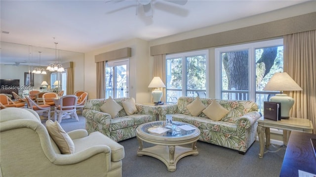 carpeted living room featuring ceiling fan with notable chandelier