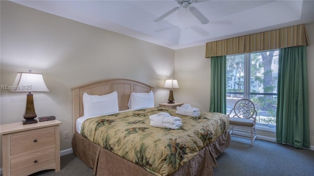 carpeted bedroom featuring a tray ceiling and ceiling fan