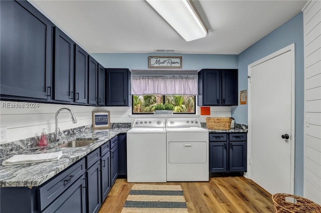 clothes washing area featuring cabinets, washer and clothes dryer, sink, and light hardwood / wood-style flooring