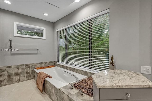 bathroom with tiled tub and tile patterned flooring